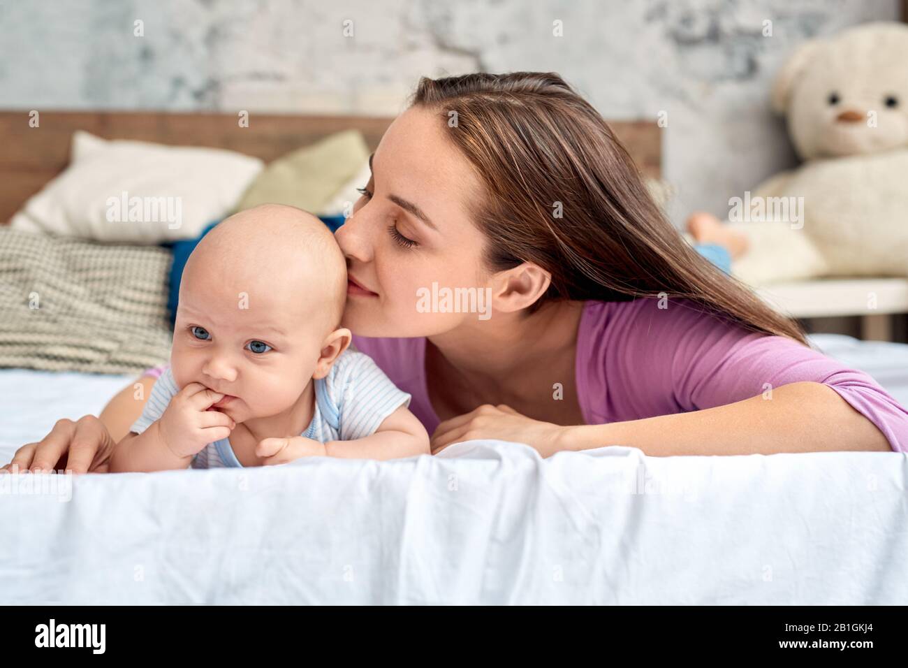 Junge Erwachsene Mutter küsst süßes kleines neugeborenes Baby Stockfoto