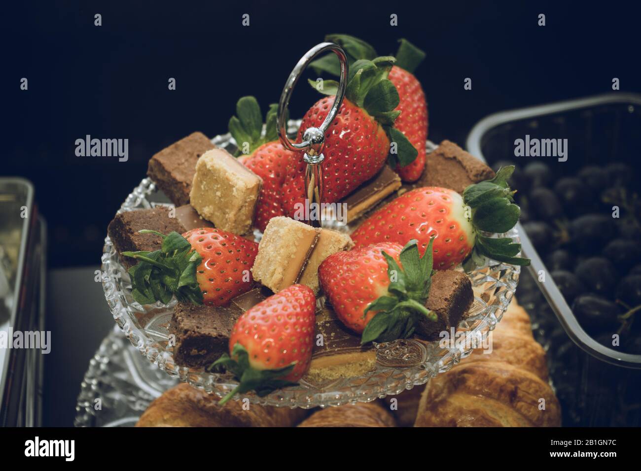 Erdbeeren und Karamelshortkuchen auf kristallgestuftem Kuchenständer Stockfoto