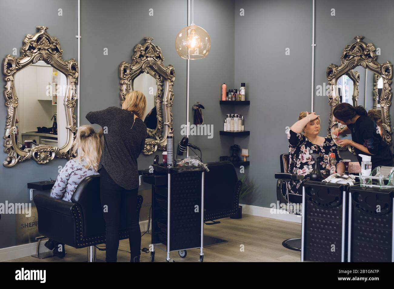 Das Innere eines Friseursalons mit einem Haarkleiderstyling und einem Makeup-Künstler, der Makeup aufgibt Stockfoto