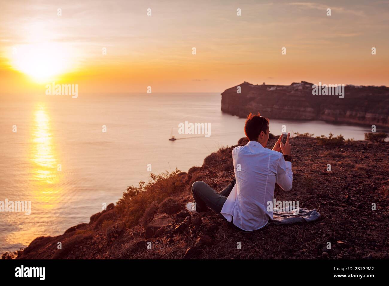 Touristen fotografieren mit dem Smartphone auf der Insel Santorini die Berglandschaft des Meeres. Mann unterwegs. Sommerurlaub Stockfoto