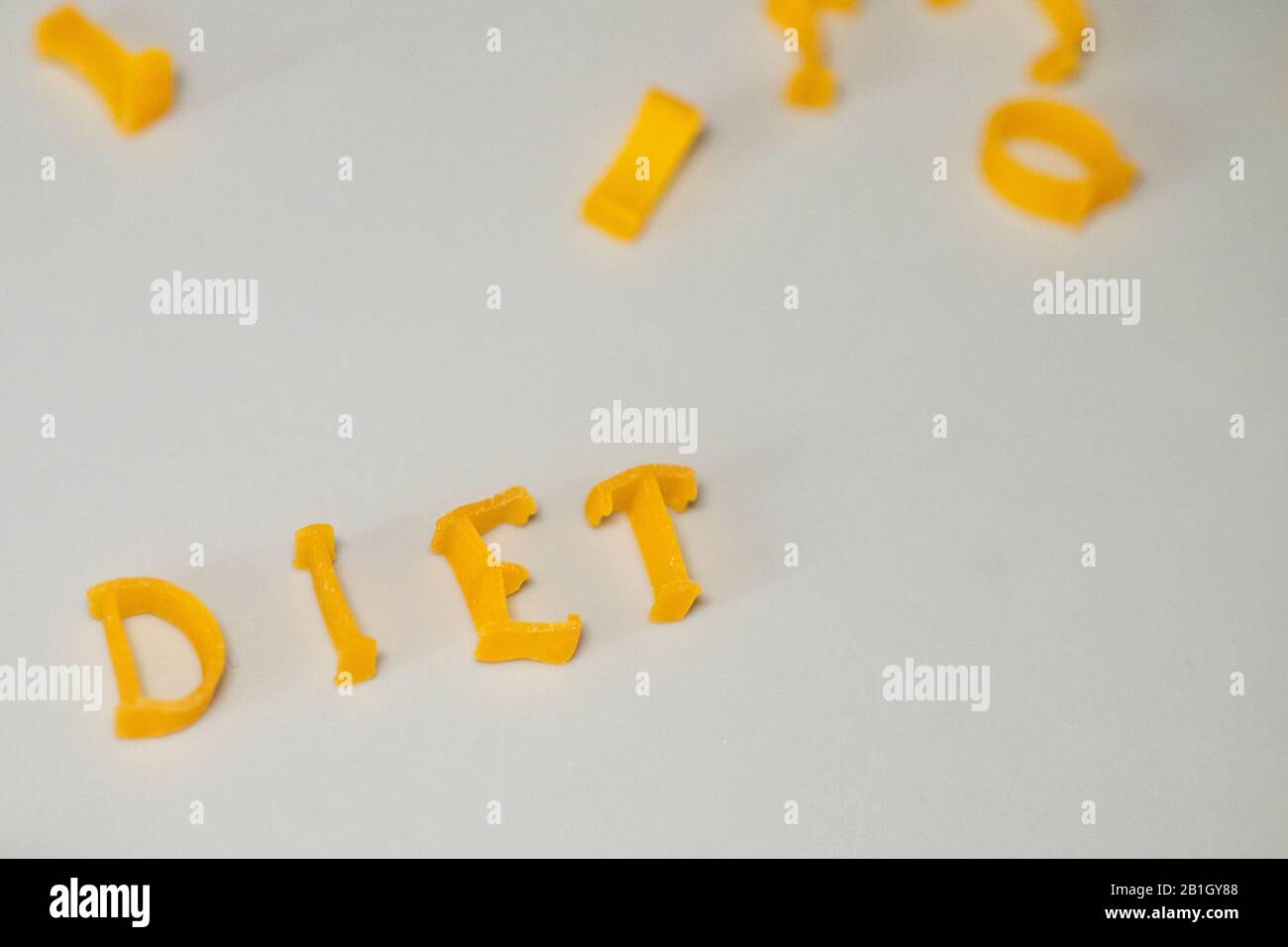 WORTDIÄT besteht aus essbaren Buchstaben. Nudeldiät Lebensmittel. Pasta in Form von Buchstaben auf grauem Hintergrund. Richtiges Ernährungskonzept. Kopierbereich Stockfoto