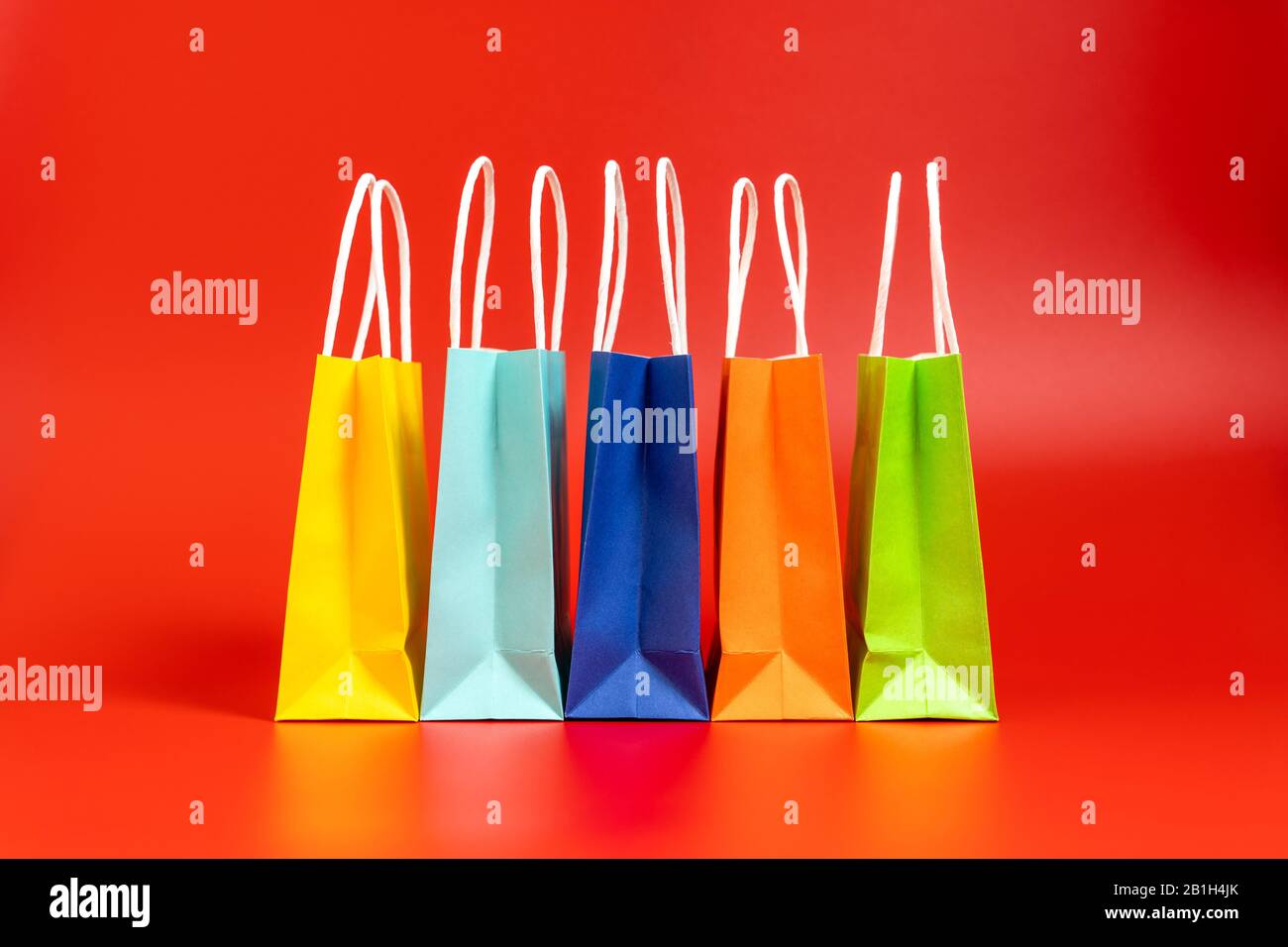 Bunte Einkaufs- oder Geschenkbeutel isoliert auf Rot Stockfoto