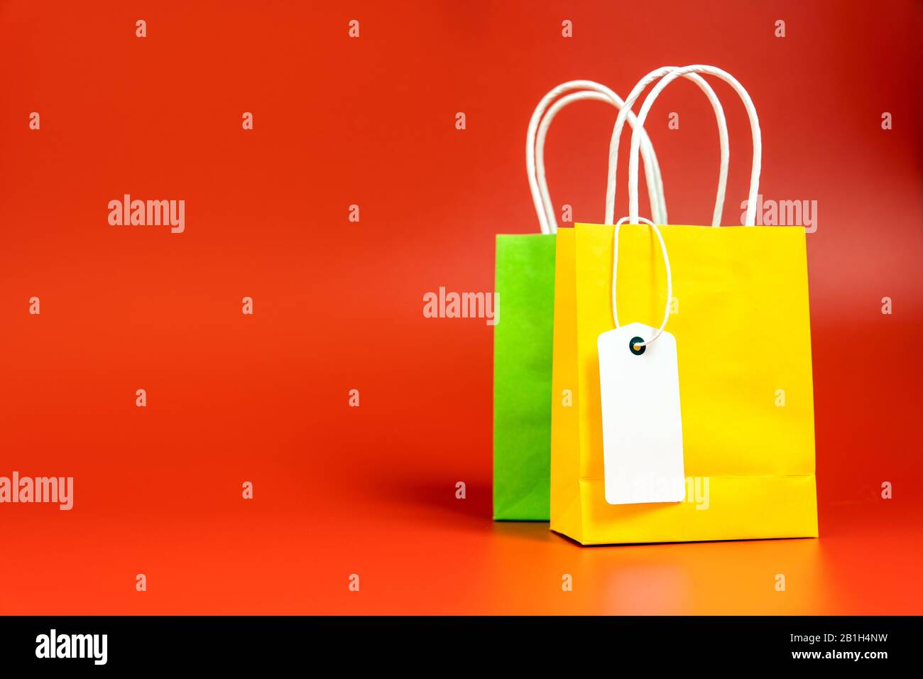 Gelbe und grüne Einkaufs- oder Geschenkbeutel isoliert auf Rot Stockfoto