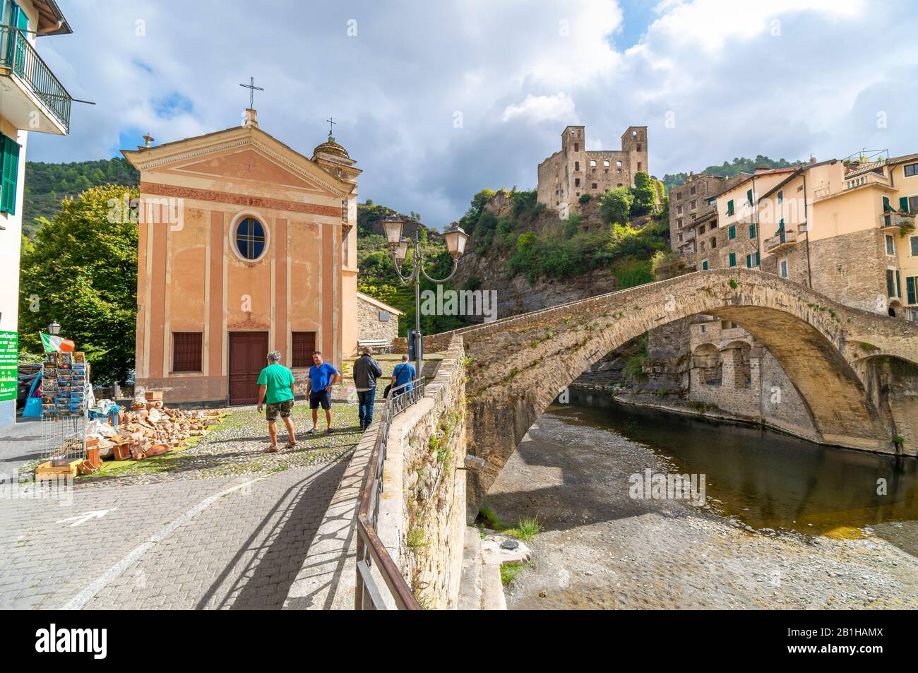 Italienische Männer arbeiten neben der Kirche San Filippo mit der alten Bogenbrücke und der Burg im Blick auf das mittelalterliche Dorf Dolceacqua Italien Stockfoto