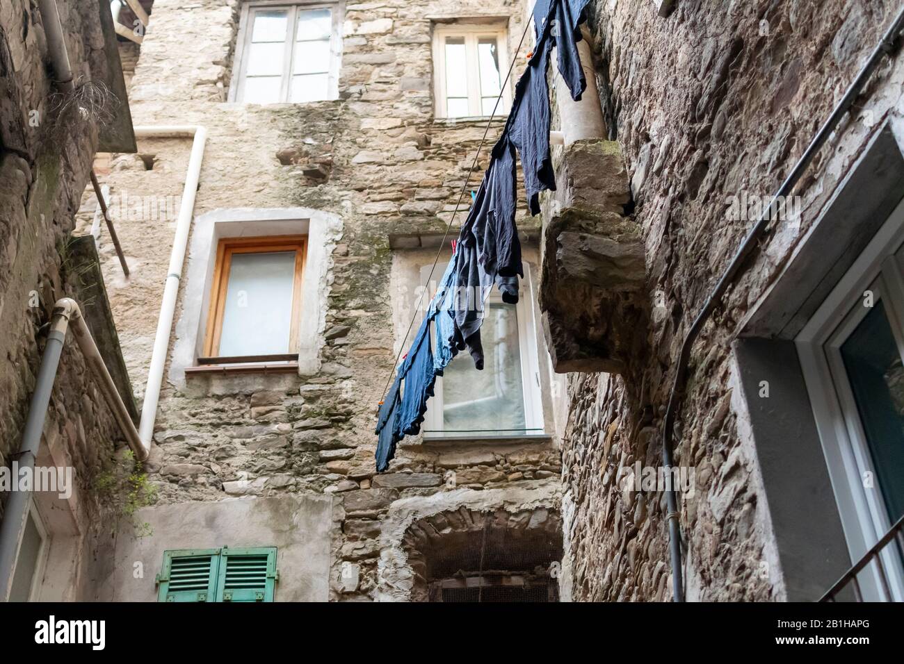 Im mittelalterlichen Steindorf Dolceacqua, Italien, hängt eine Auswahl blauer Kleidung an einer Wäscheleine. Stockfoto