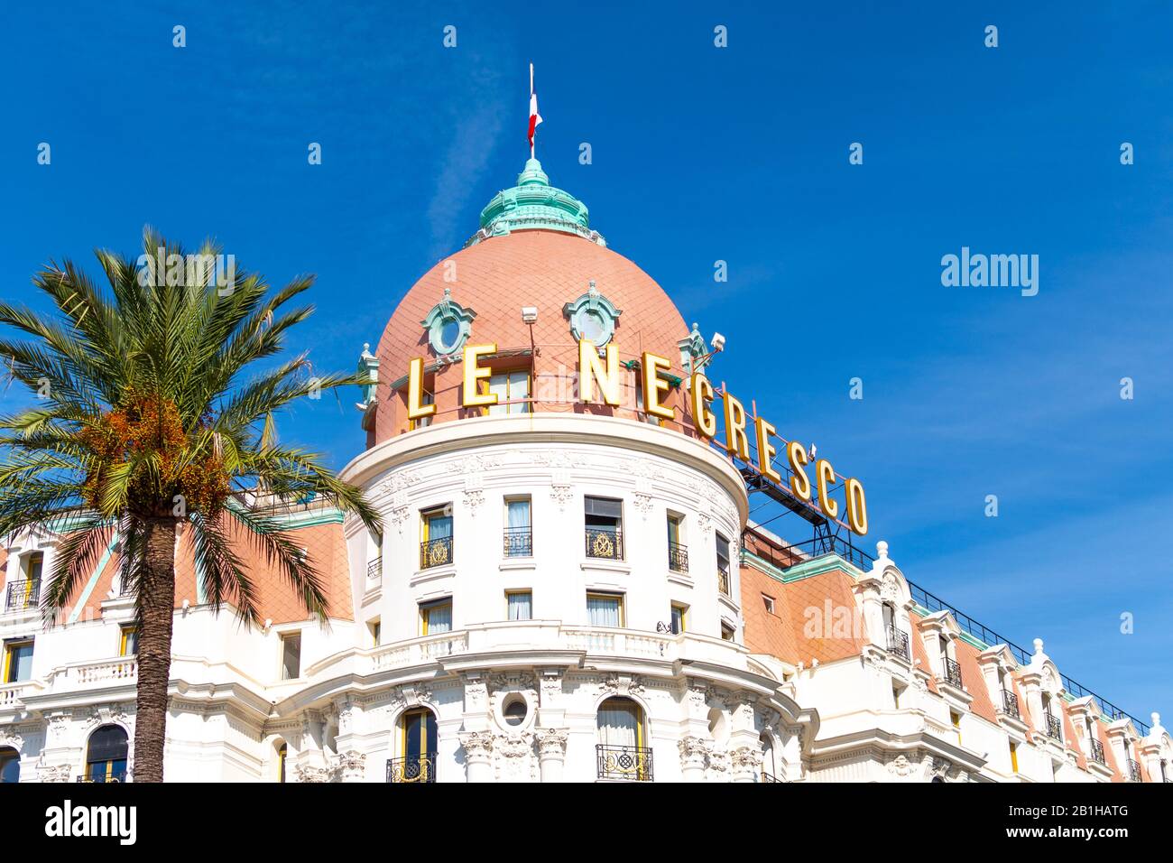 Palmenbaum und das luxuriöse Strandhotel Negresco an der Promenade des Anglais an der französischen Mittelmeerküste von Nizza. Stockfoto