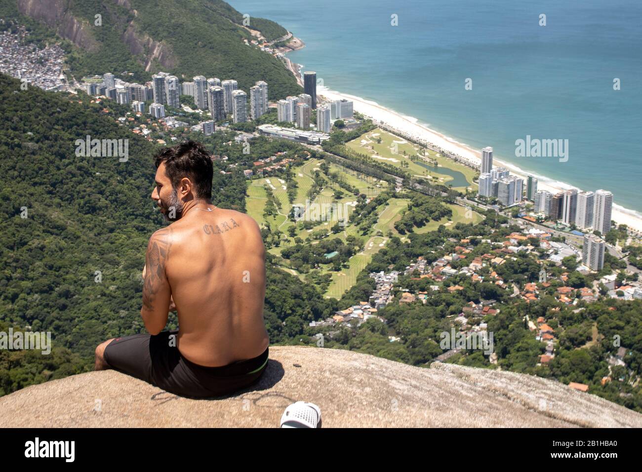 Mann von hinten gesehen, mit Blick vom beliebten Wander-Aussichtspunkt Pedra Bonita über das Viertel São Conrado mit Golfplatz Stockfoto
