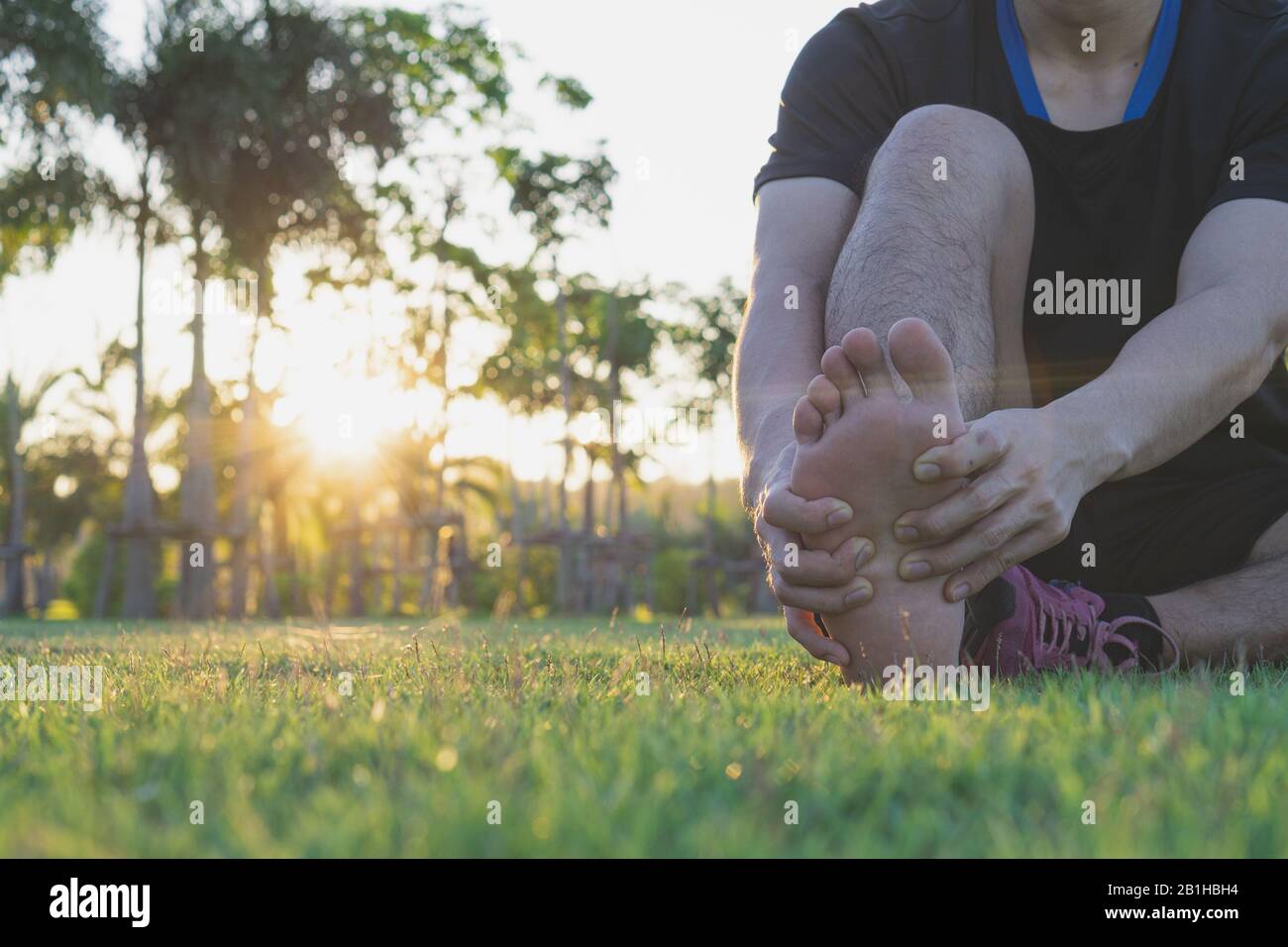 Junge Mann seine schmerzhaften Fuß massieren vom joggen und laufen auf der Laufstrecke. Sport und Bewegung Konzept. Stockfoto