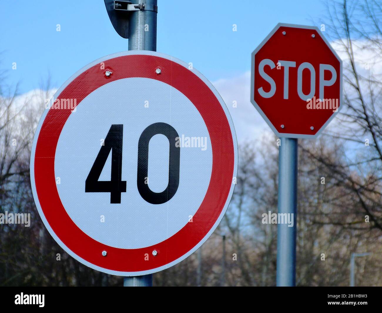 Weißes Rundfahrts- und Verkehrszeichen mit roter Umrandung und der Zahl von 40, die die Geschwindigkeit begrenzen und maximieren. Hellblauer Himmel und weiße Wolken darüber. Stockfoto