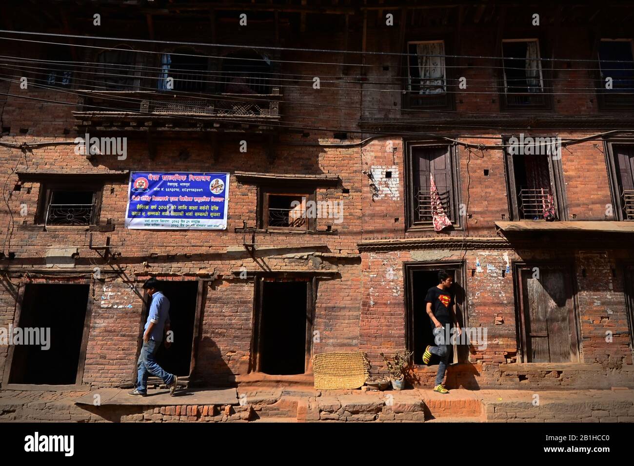 Junge Männer, die in entgegengesetzte Richtungen laufen, fotografiert in der Wohngegend der Altstadt von Bhaktapur, Nepal. Stockfoto