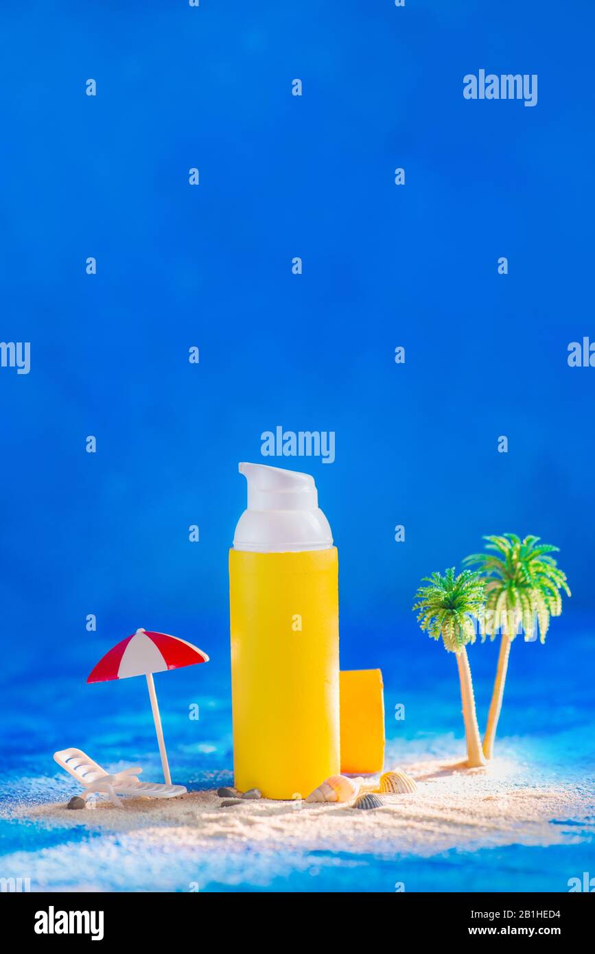 Sonnenschutzcreme mit Miniaturpalmen, Regenschirm und Liegestuhl an einem Strand. Hautpflegekonzept Stockfoto