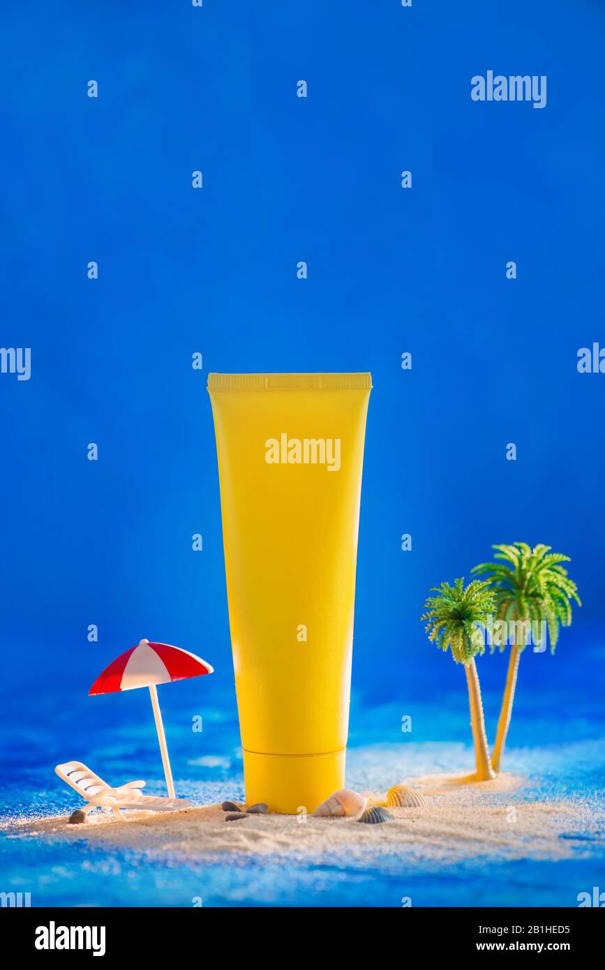 Sommerliches Hautpflegekonzept mit Sonnenschutzrohr und Miniaturpalmen, blauer Hintergrund mit Kopierraum Stockfoto