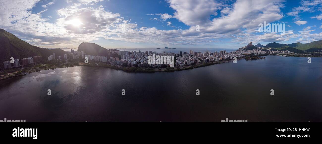Luftbild 180 Grad Blick auf den Rio de Janeiro Stadtsee Lagoa Rodrigo de Freitas mit intensivem blauem Himmel und Sonne hinter einer Wolke über Ipanema Stockfoto