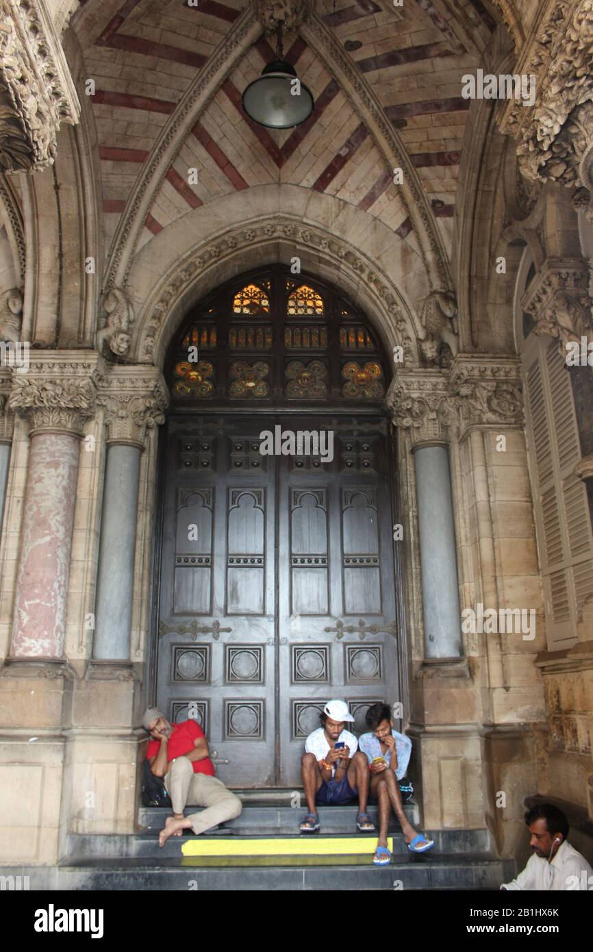 September 2019 In Mumbai, Maharashtra, Indien. Leute, die Chhatrapati Shivaji Maharaj Terminus oder Victoria Terminus Bahnhof sitzen Stockfoto
