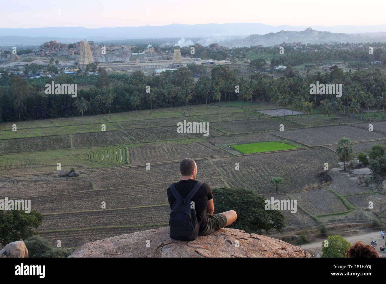 Dezember 2019, Hampi, Karnataka, Indien. Mann, der auf dem Sonnenuntergang am Felsen sitzt, Hippie-Insel Stockfoto