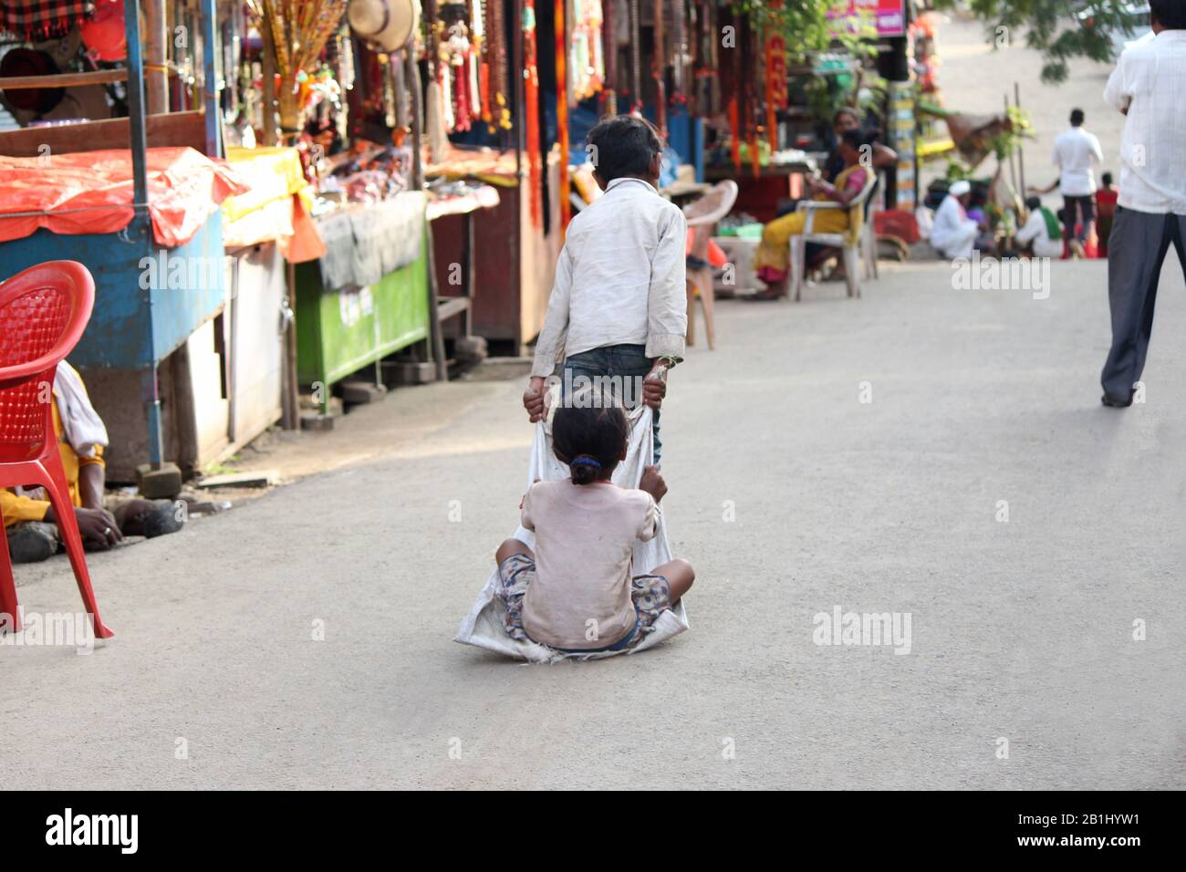 September 2019, Pune, Maharshtra, Indien. Kinder, die auf der Straße spielen, Junge, der Mädchen mit Bettlaken trägt Stockfoto