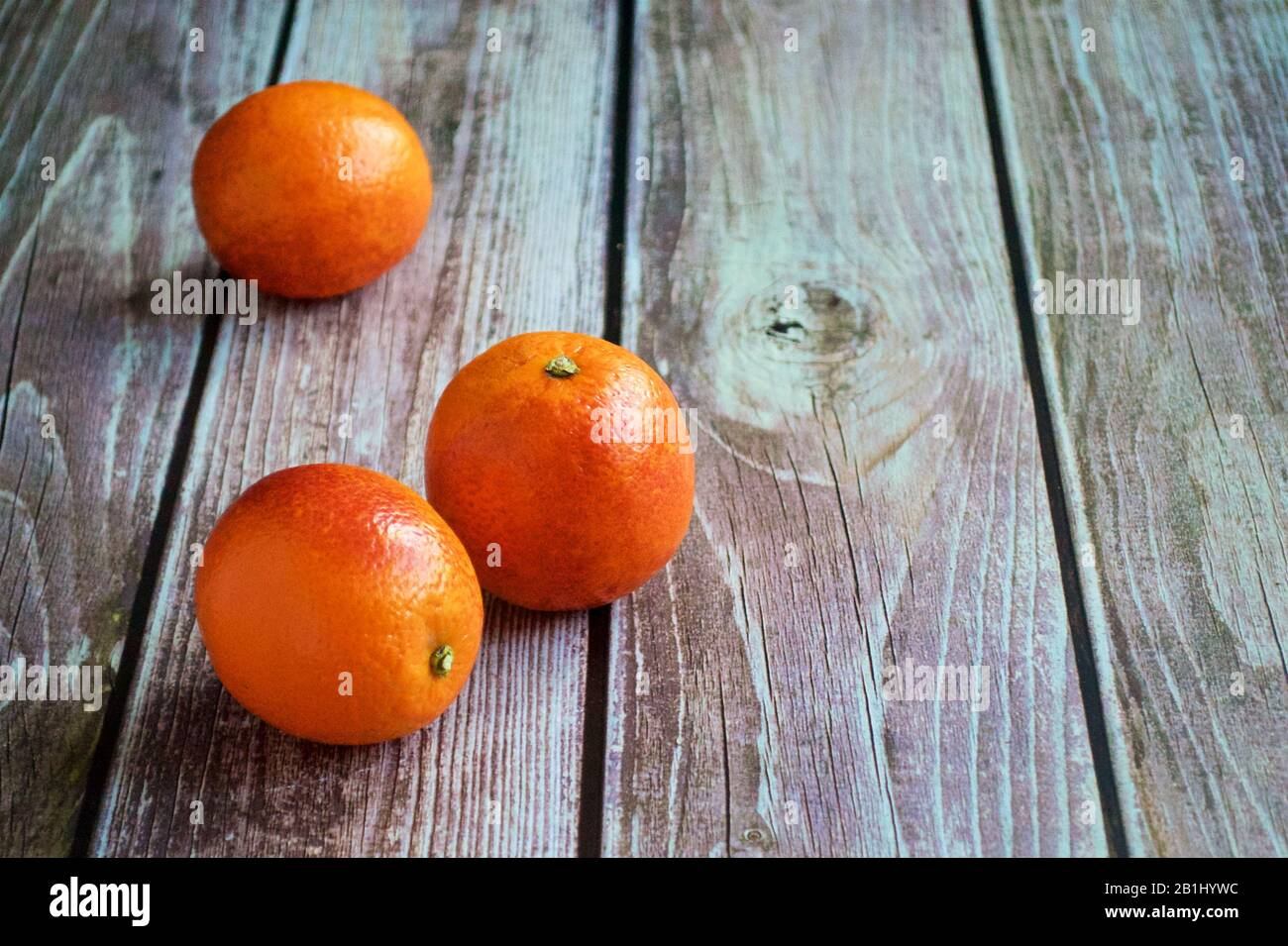Auf einem Holztisch liegen drei rote Orangen Stockfoto