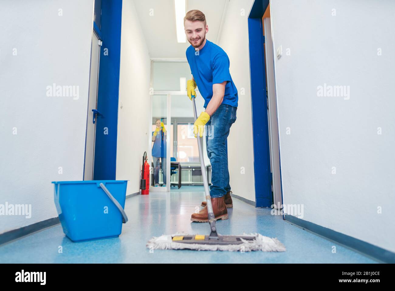 Sauberer Mann, der den Boden in einer Halle wischen kann Stockfoto