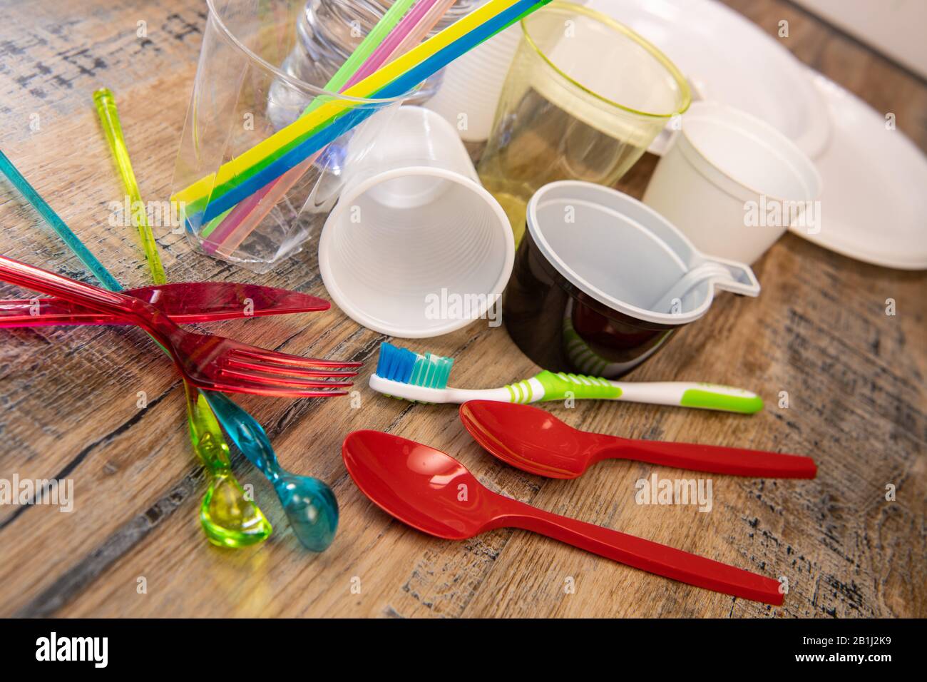 Plastikmüll, verschiedene Plastikutensilien, Umweltschutz auf Holzhintergrund Stockfoto