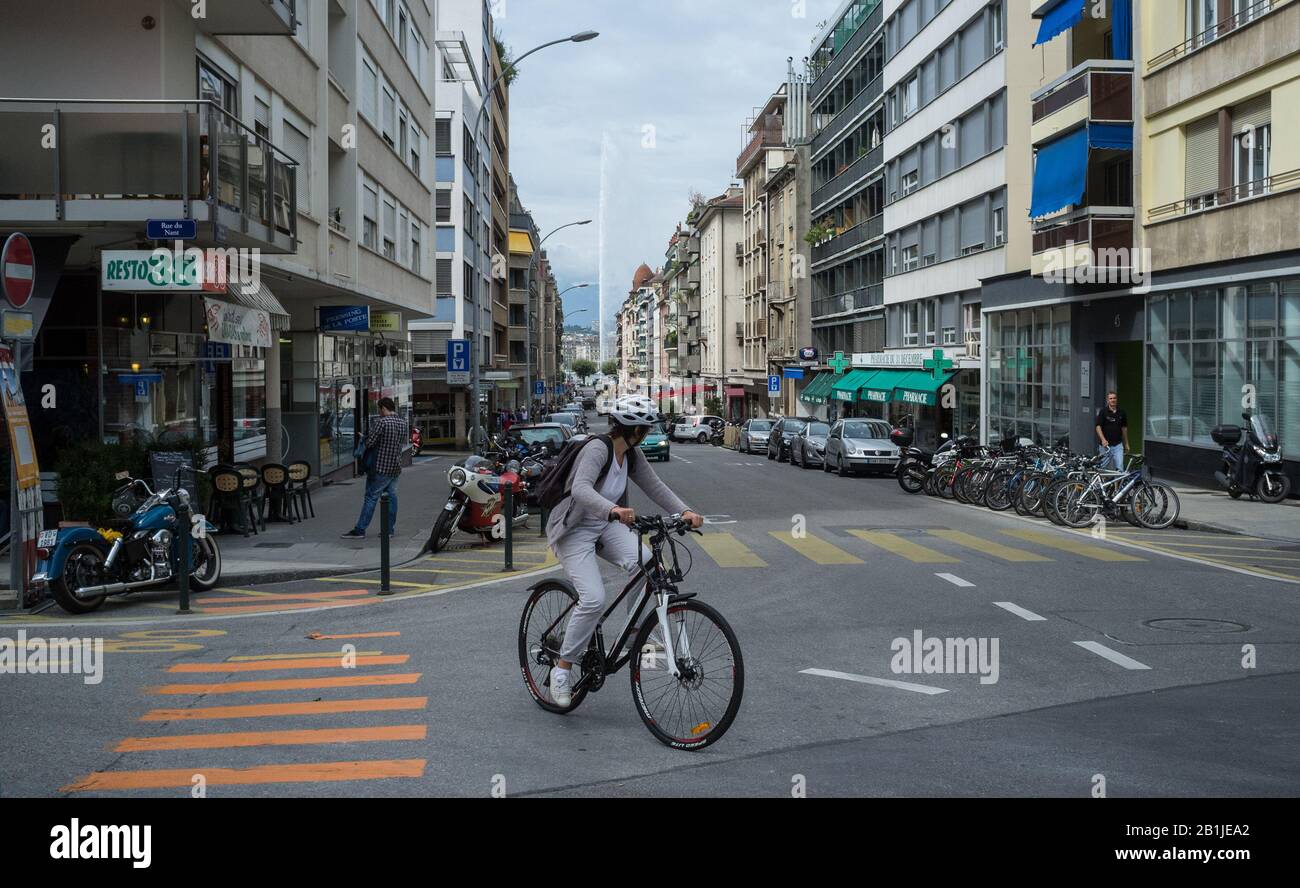 September 2014 Schweiz Genf. Ein junges Mädchen in einem Schutzhelm fährt auf einer Straße in Genf mit dem Fahrrad. Stockfoto