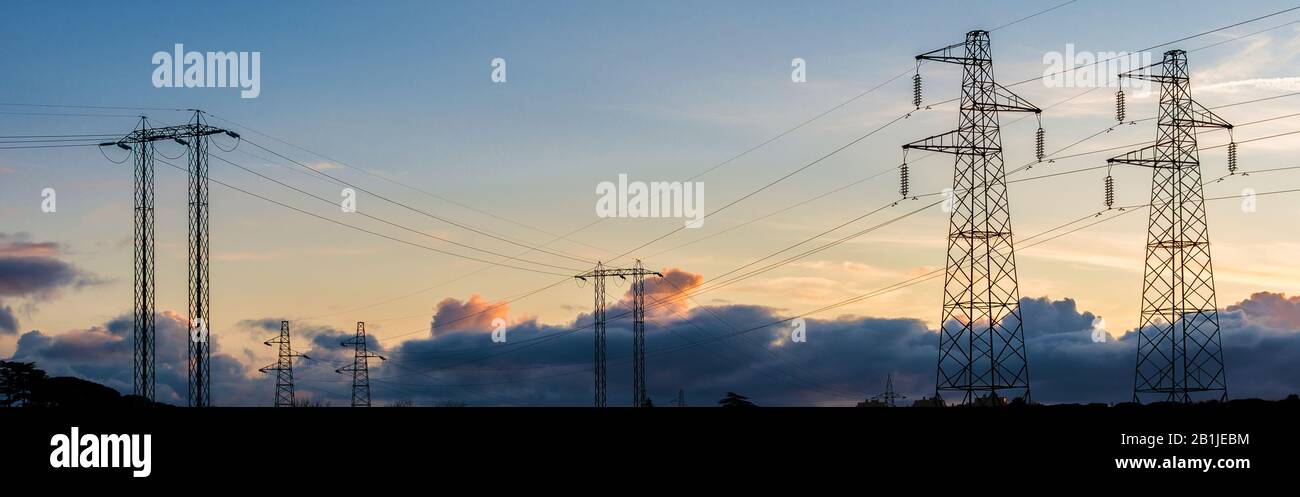 Stromkabel. Sendetürme oder Elektrizitätspylone mit Himmel bei Sonnenuntergang Stockfoto