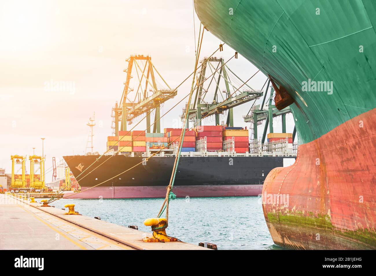 Hafenbeneidung: Schiffskräne entladen Container von einem Schiff. Transportindustrie und Versandlogistik. Exportieren und Importieren von Bussinen. Stockfoto