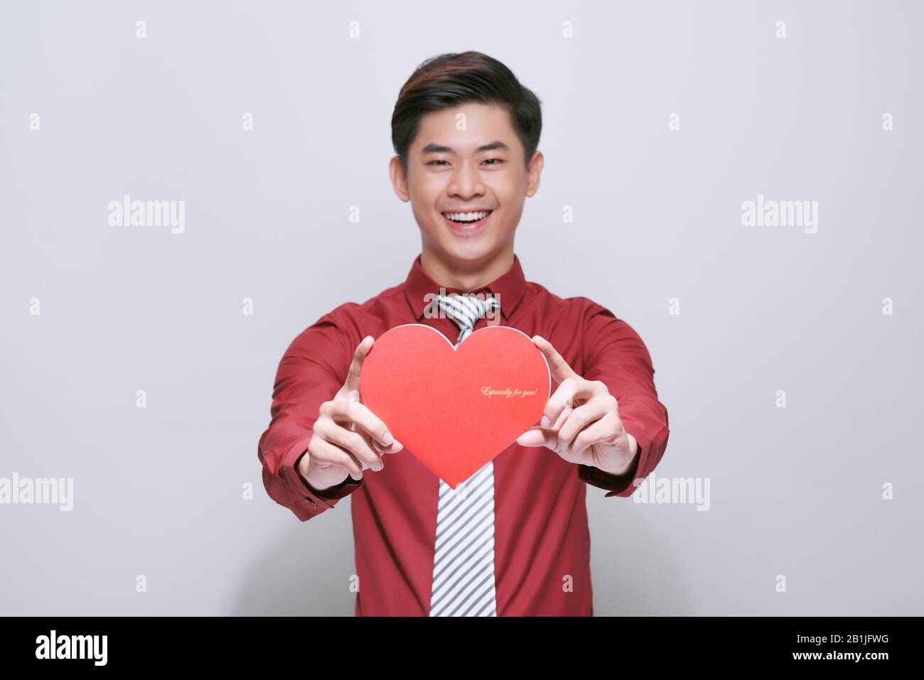 Süße, hübsche asiaten halten ein rotes Herz aus Papier für den Valentinstag auf weißem Hintergrund mit Platz für Kopien aus Stockfoto