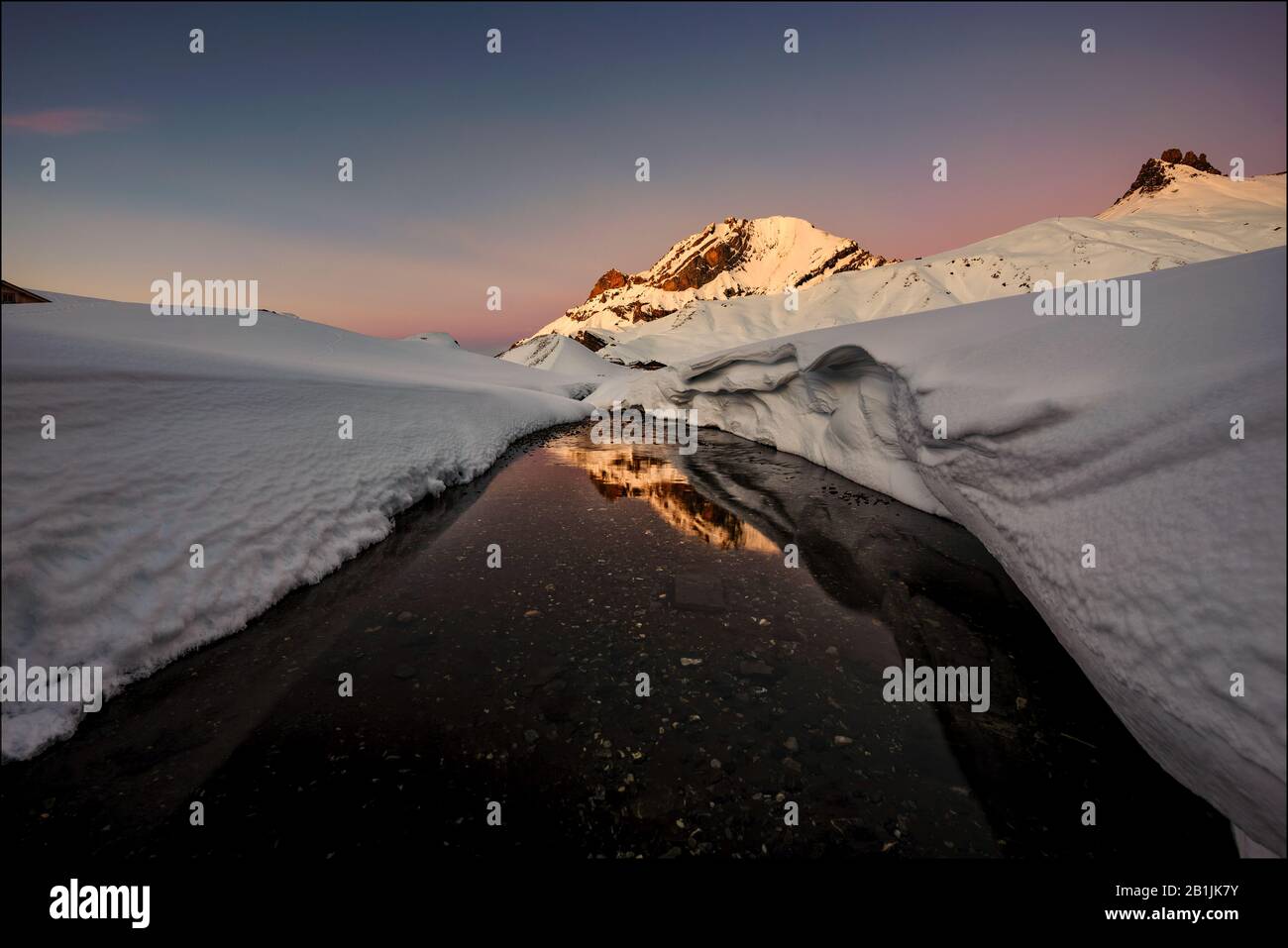 Langsam fließende Engstligen in Schneefräsen, die den sonnendurchfluteten Lohner Gipfel in der Abenddämmerung widerspiegeln Stockfoto