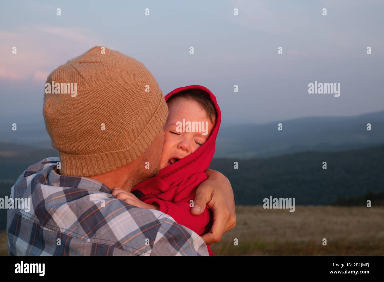 Der Sohn sitzt auf den Schultern seiner Väter in den Frühlingsbergen. Familiencamping. Reisen mit Kinderkonzept Stockfoto