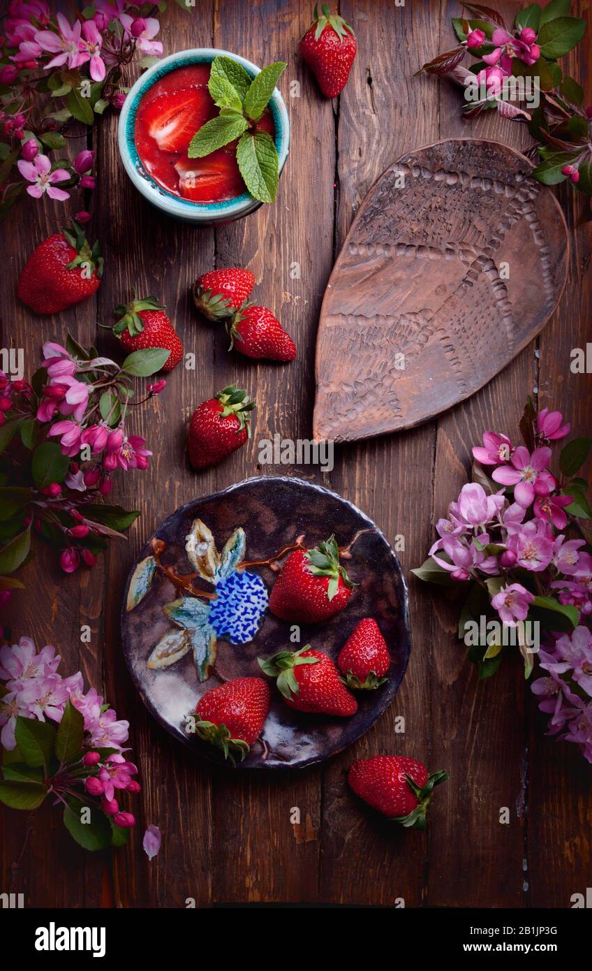 Flatlay Food Background - leeres Holzbrett mit Erdbeeren, frischen Smoothie und pinken Blumen, Platz für Text kopieren Stockfoto