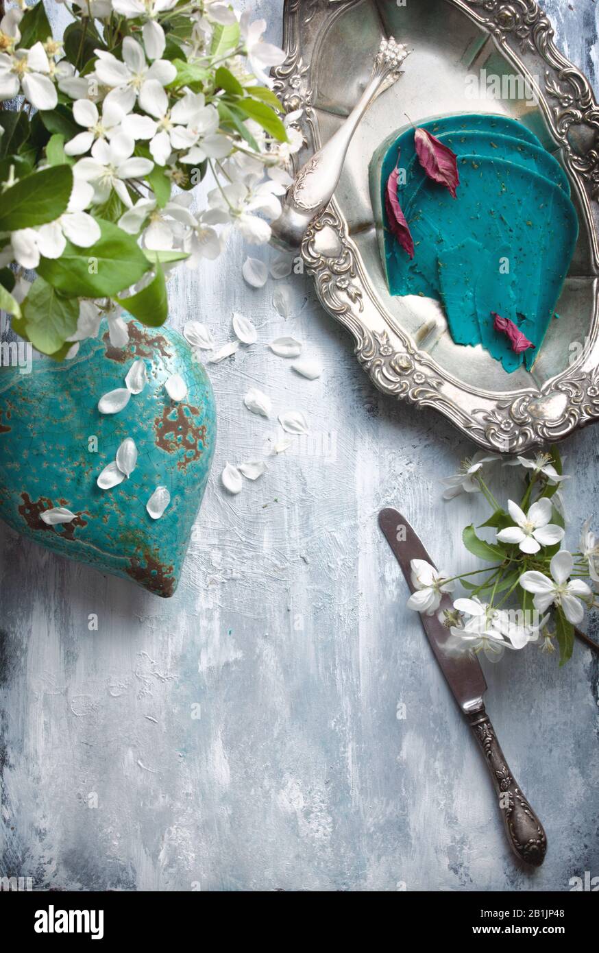 Flatlay essen Hintergrund - leere Holztisch mit Blauschimmelkäse Stücke, weißen Blüten und Silber Antik dishwear Stockfoto