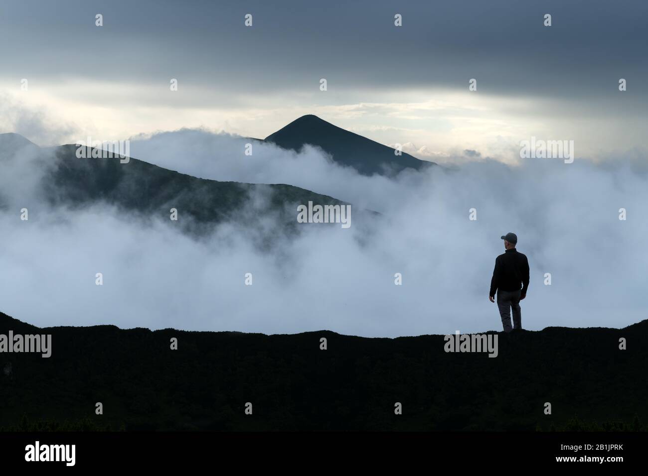 Mann Silhouette auf bewölkten Bergen. Reisekonzept. Landschaftsfotografie Stockfoto