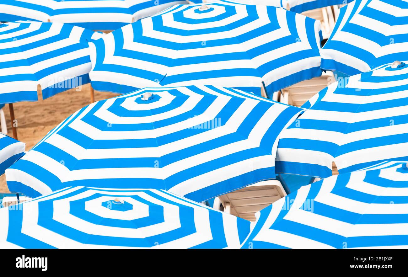 Gestreifte blau-weiße Regenschirme. Abstraktes Hintergrundfoto im Sommer am Strand am sonnigen Tag Stockfoto