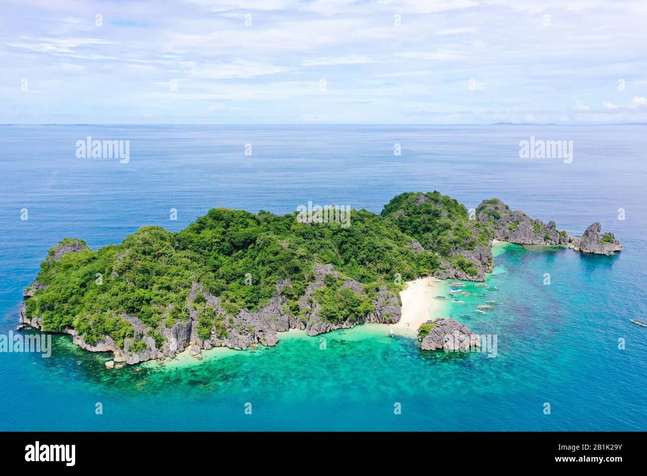 Tropische Landschaft: Matukad Insel mit schönem Strand und Touristen durch türkisfarbenes Wasser Blick von oben. Karamoische Inseln, Philippinen. Sommer- und Reiseurlaubskonzept. Boote und Touristen am Strand. Stockfoto
