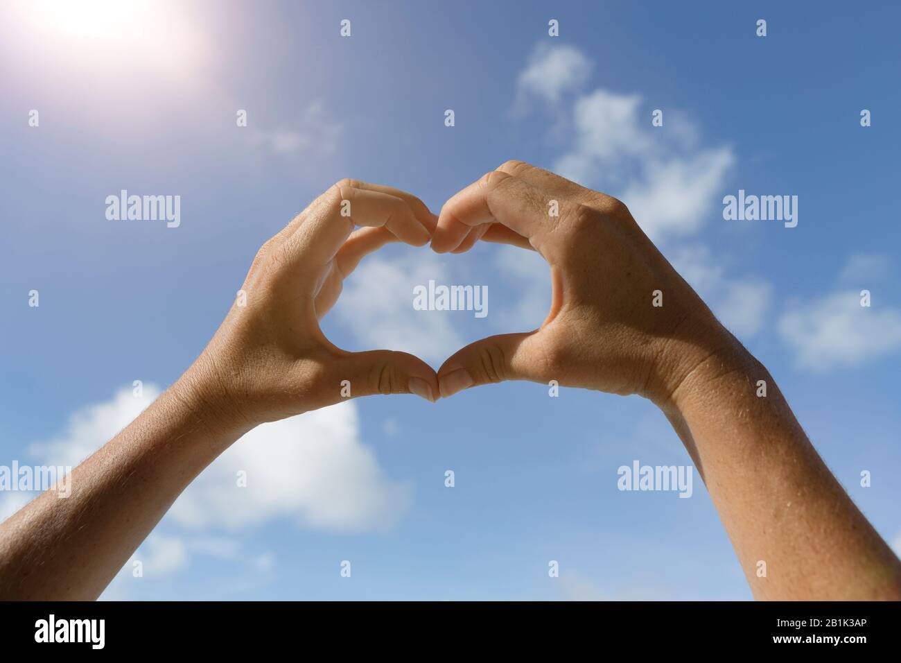 Herzhände Symbol vor blauem sonnigen Himmel Stockfoto