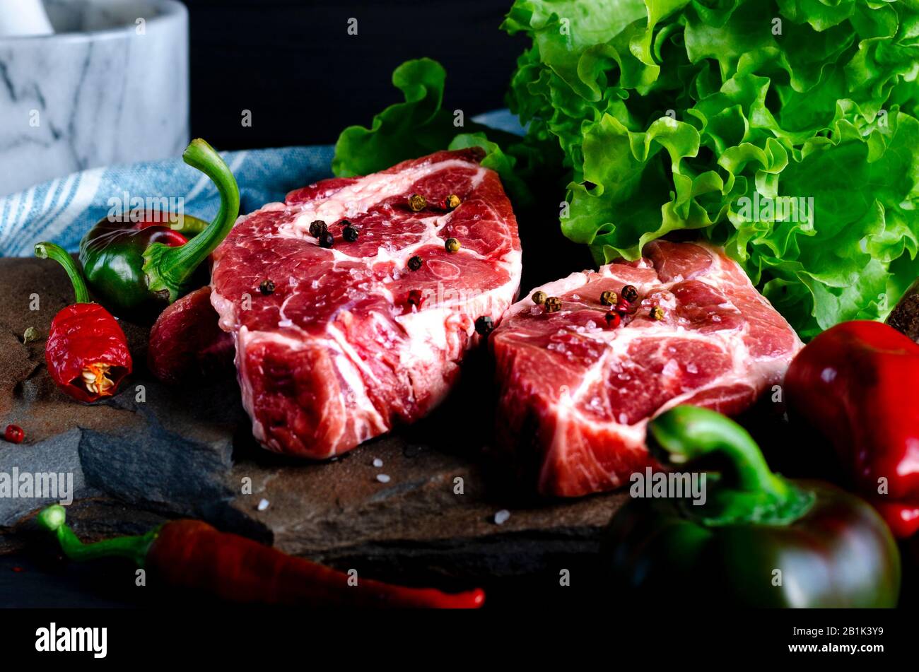 Fleischkonzept. Fleischsteaks können mit auf dem Tisch liegendem Gemüse zubereitet werden Stockfoto