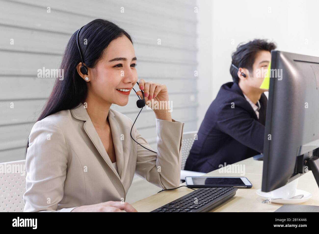 Lächelnder asiatischer Callcenter-Betreiber arbeitet im Büro und spricht mit dem Kunden. Stockfoto