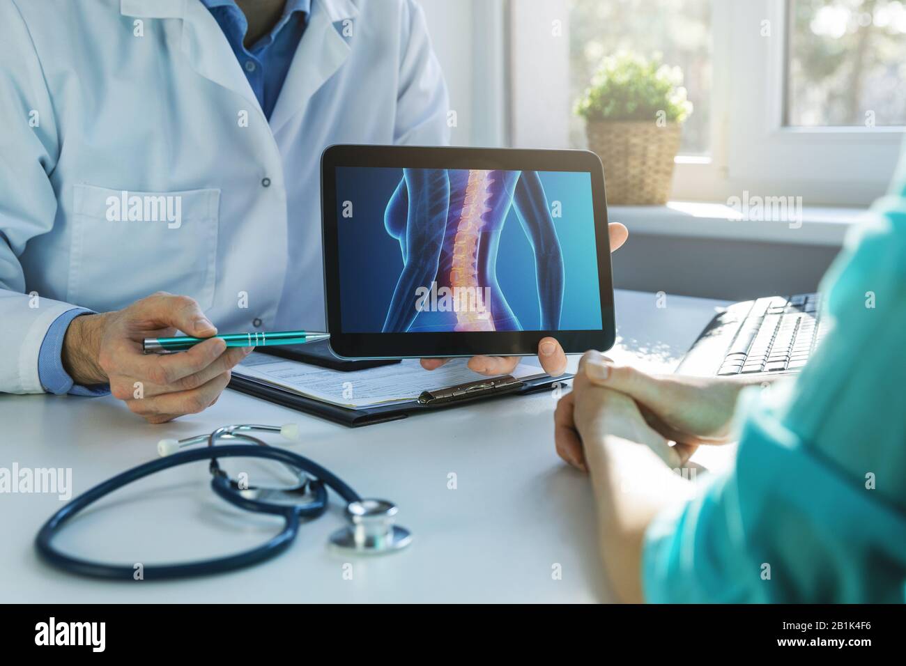 Arzt und Patient sprechen über Rückenschmerzen in der Klinik Stockfoto