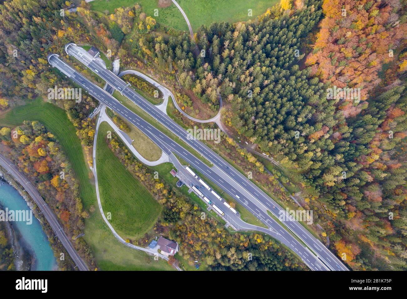 Top Dämmerung Luftbild von Freeway Geschwindigkeit Straße von U-Bahn Tunnel zwischen Gelb Herbst Wald Bäume und Blue River. Stockfoto