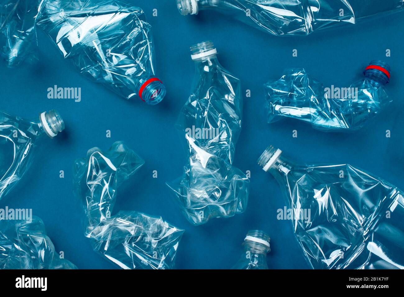 Viele gebrauchte Plastikflaschen auf blauem Hintergrund. Das Konzept der Verschmutzung des Planeten und der Ozeane durch Plastikmüll. Stockfoto