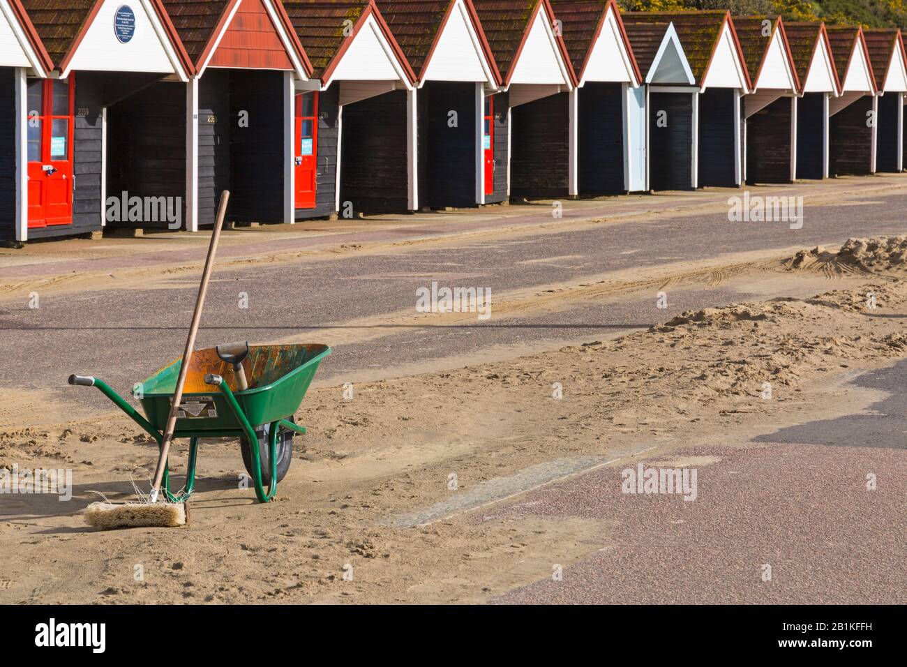 Pinsel, Spaten und Schubkarre bereit, um Sand von der Promenade aus vor kurzem schlechtem Wetter in Bournemouth, Dorset UK an einem sonnigen kalten Tag im Februar zu entfernen Stockfoto