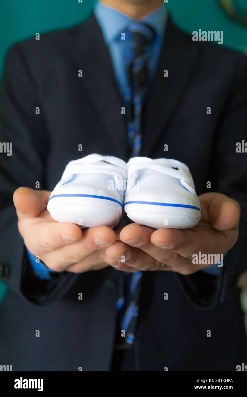 Elegante Herrenhände mit Babyschuhen Stockfoto