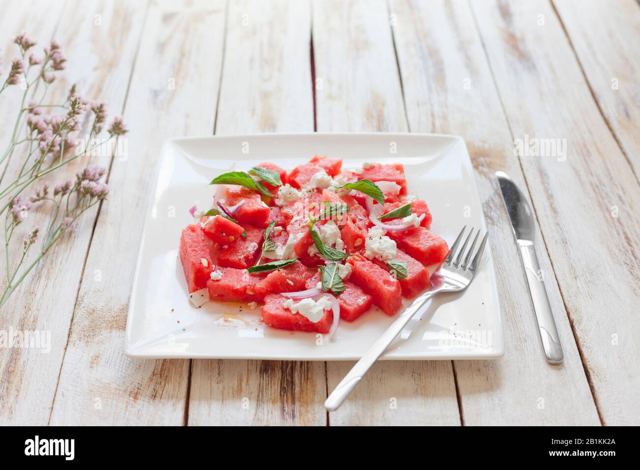 Frischer Wassermelonsalat mit Fetakäse und Minze auf weißem Teller Stockfoto