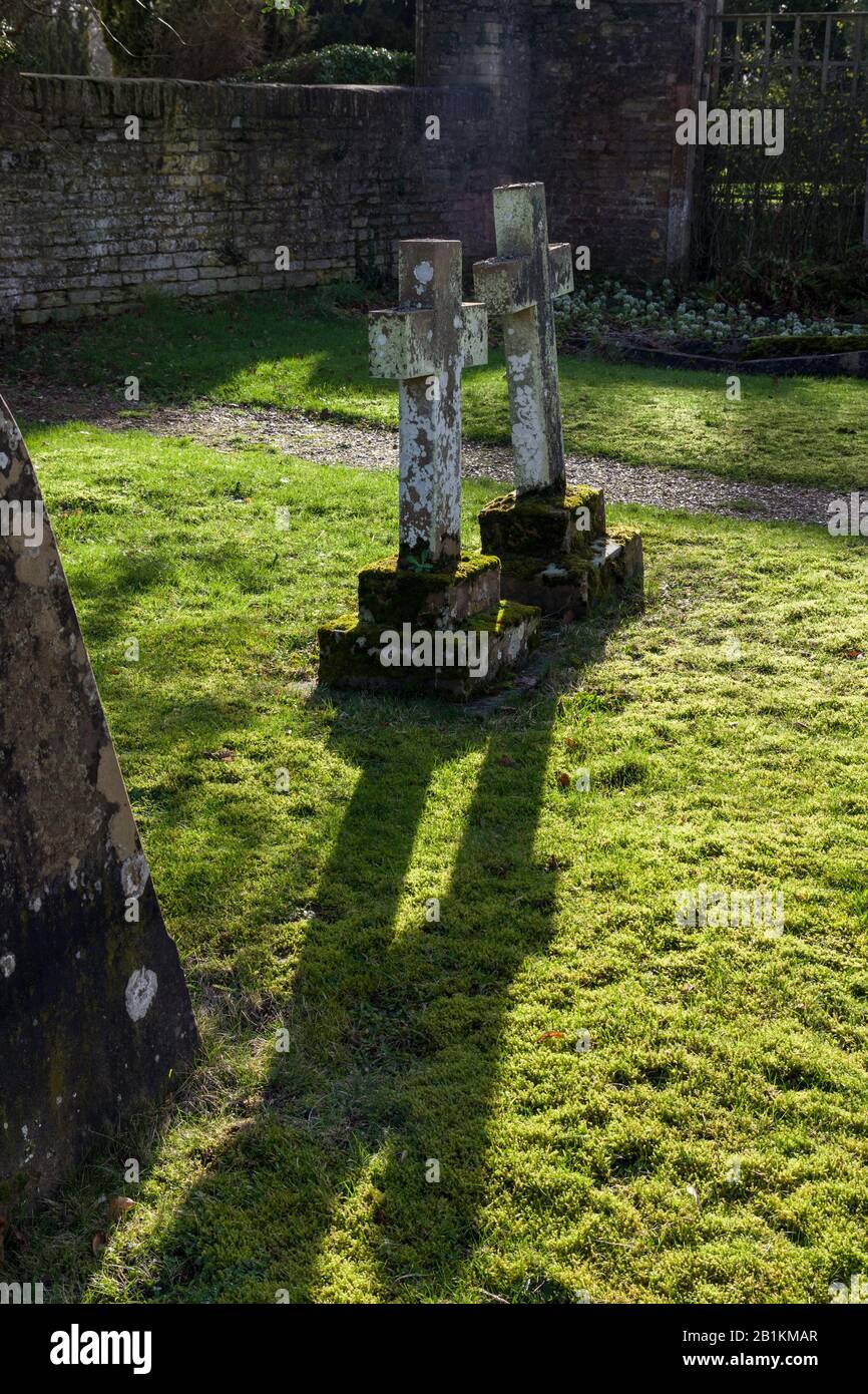 Zwei Gegenlichtsteinkreuze, die lange Schatten werfen, im Kirchenhof von St Mary Magdala, Castle Ashby, Northamptonshire, Großbritannien Stockfoto