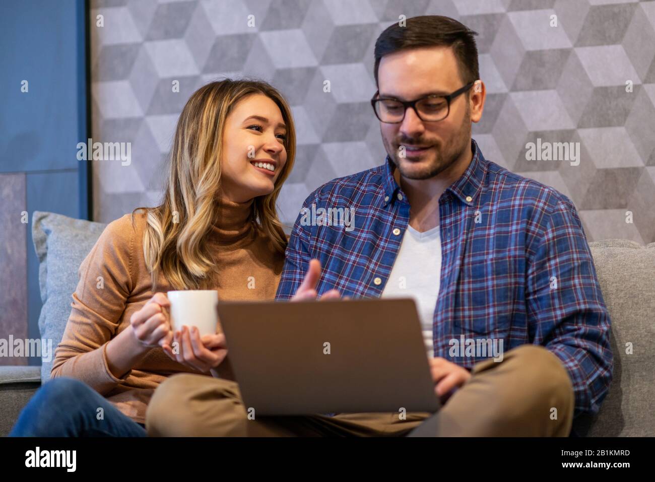 Junges Paar mit Laptop zu Hause. Sie surfen mit Laptop im Netz.Menschen und Technologiekonzept. Stockfoto