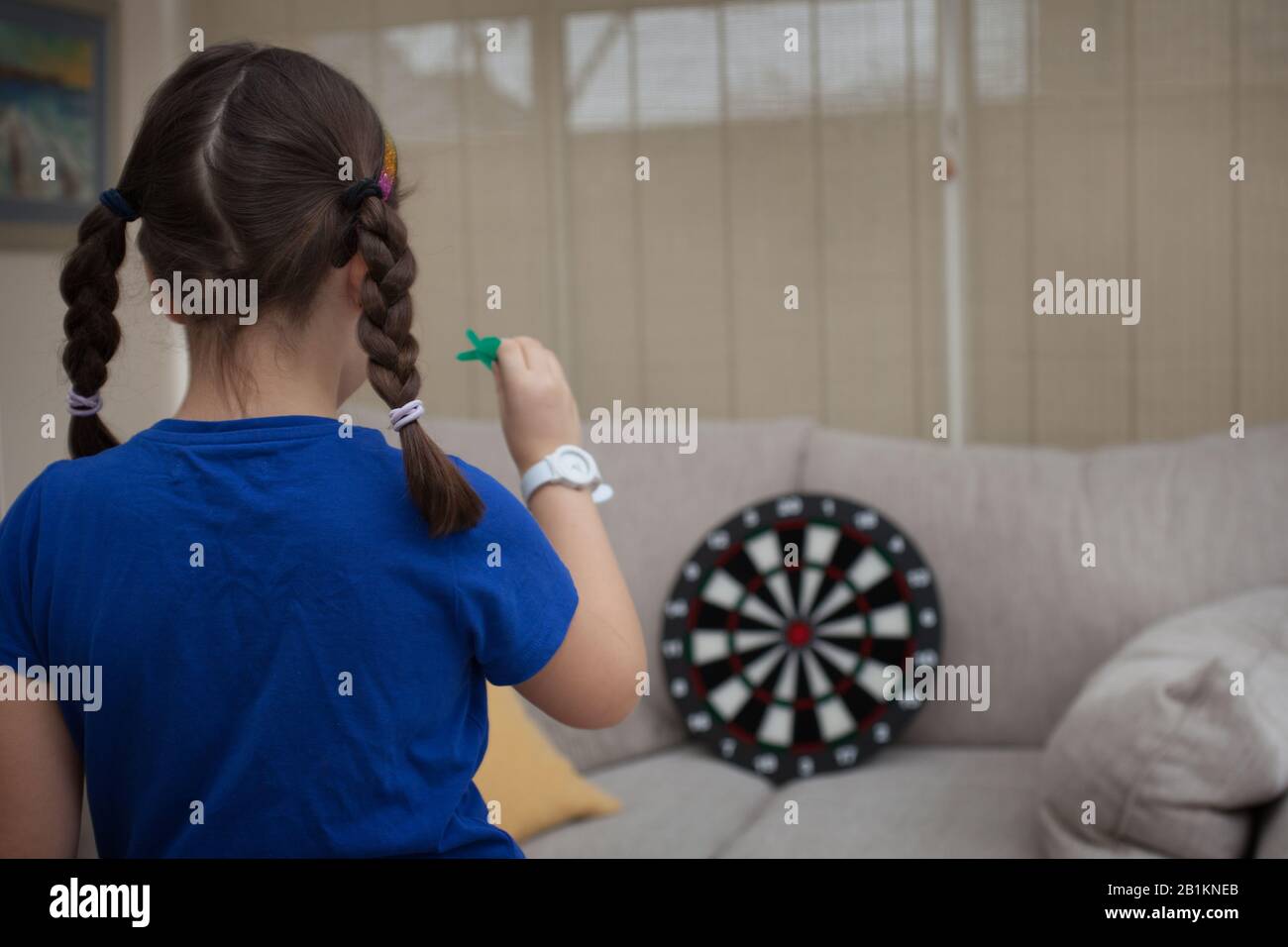 Ein junges Mädchen, das zuhause Darts spielt Stockfoto