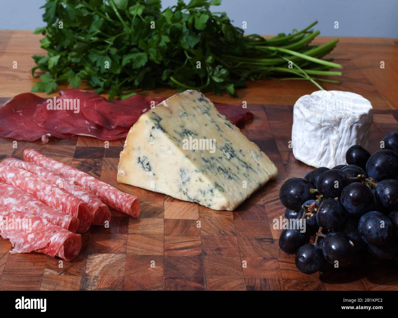 Eine Auswahl an italienischem Aufschnitt, Käse, frischen Kräutern und Trauben Stockfoto