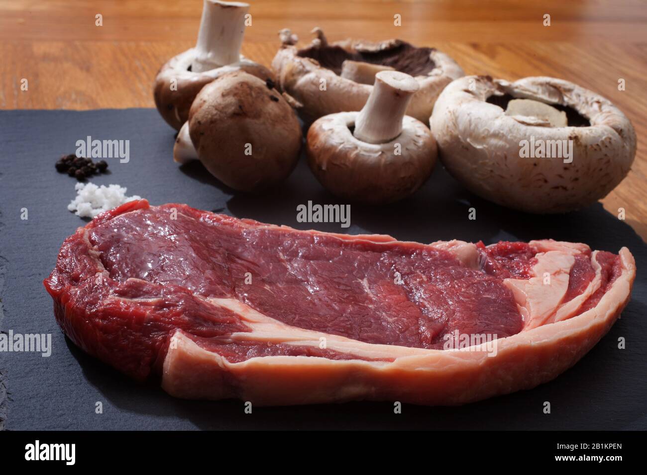 Rohes Rib Eye-Steak, Pilze, Salz und Pfeffer zum Kochen bereit Stockfoto