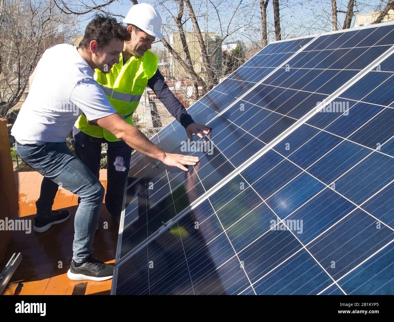 Kaukasischer erfahrener Techniker, der die Solarpaneele seinem jungen Kunden zeigt. Alternative Stromquelle, nachhaltige Ressourcenkonzeption. Stockfoto