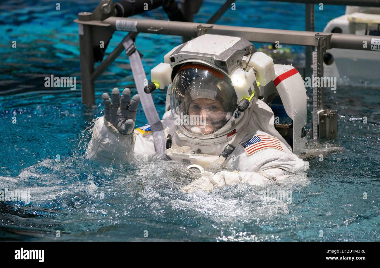 Astronautin Anne McClain winkt Beobachtern, als ein Oberkran sie in den Neutral Buoyancy Lab Pool der NASA für das Schwerelosigkeitstraining in Houston senkt. Der 6,2 Millionen Liter fassende Pool enthält eine Verspottung der Internationalen Raumstation (ISS). Stockfoto